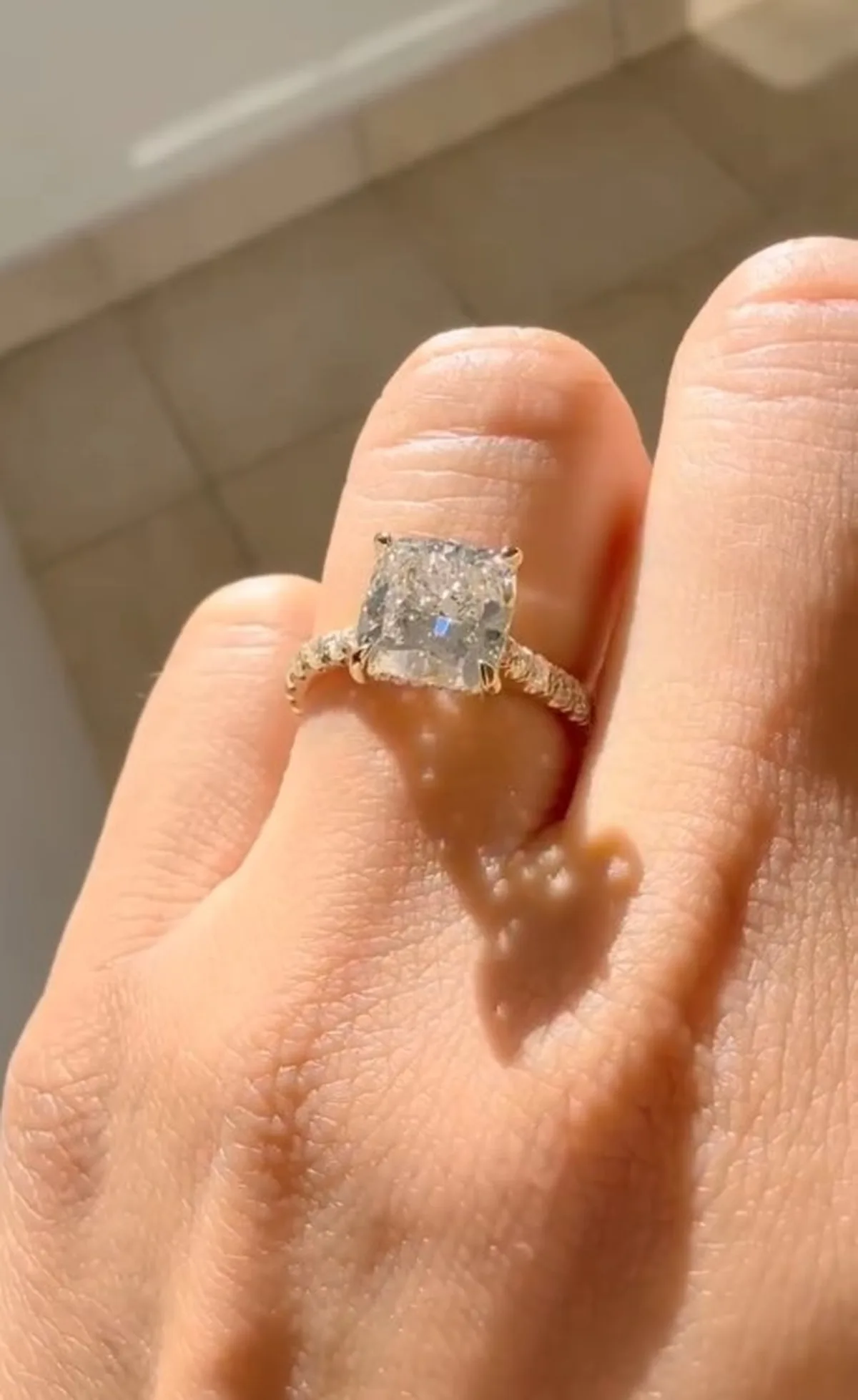 Cushion cut lab-grown diamond engagement ring with pave band in yellow gold on hand, Haejin Jewelry Brooklyn