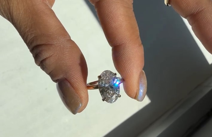 Oval lab-grown diamond with rainbow fire, held in natural light at Haejin Jewelry Brooklyn