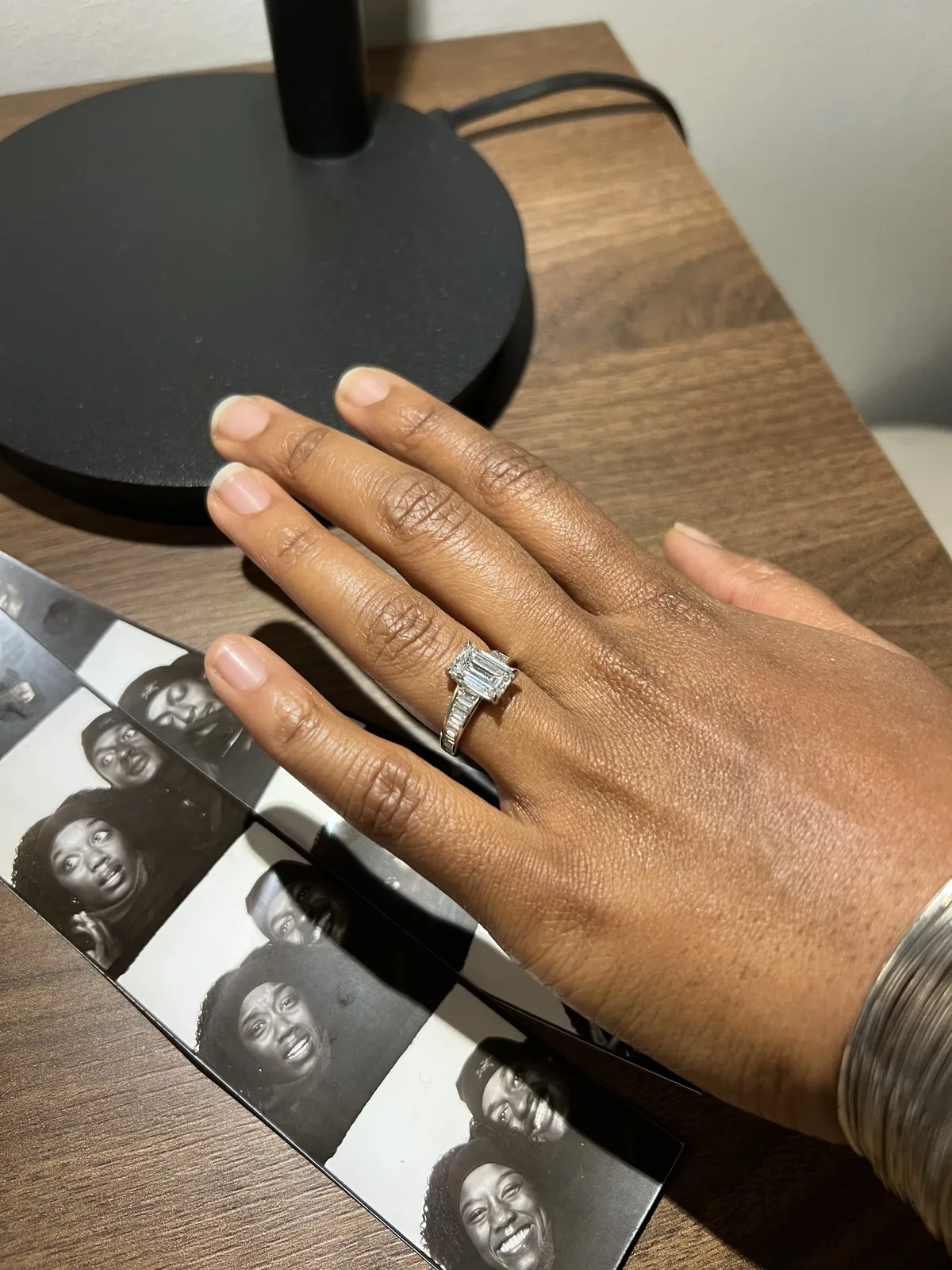 Custom emerald cut engagement ring on hand next to photo booth pictures, Haejin Jewelry Brooklyn