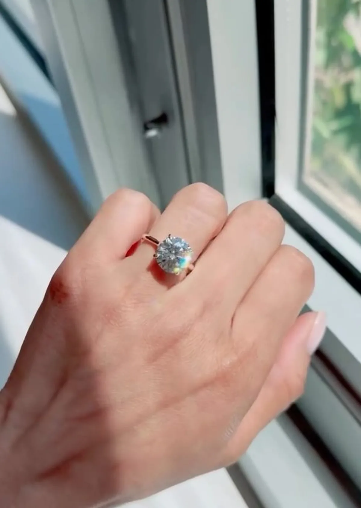 Round solitaire lab-grown diamond engagement ring in yellow gold on hand by window, Haejin Jewelry Williamsburg Brooklyn