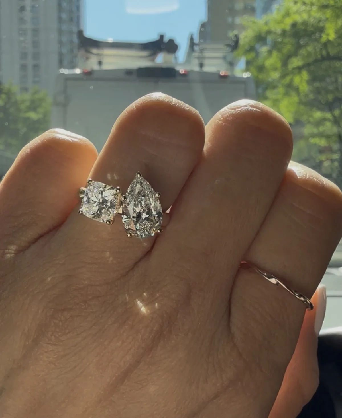 Toi et moi engagement ring with cushion and pear lab-grown diamonds on hand in natural light, Haejin Jewelry NYC