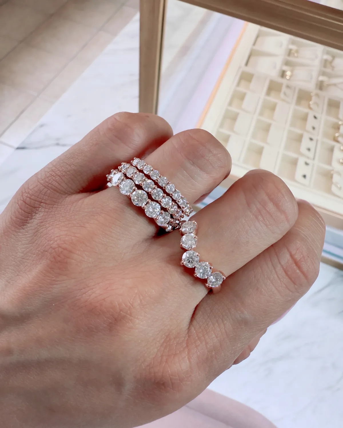Diamond eternity bands on hand with Haejin Jewelry Brooklyn studio display case and marble counter in background