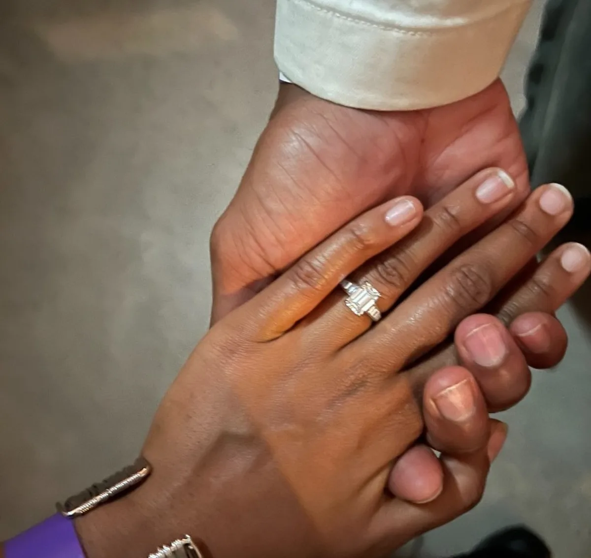 Couple wearing Haejin Jewelry wedding bands and engagement ring with flower bouquet