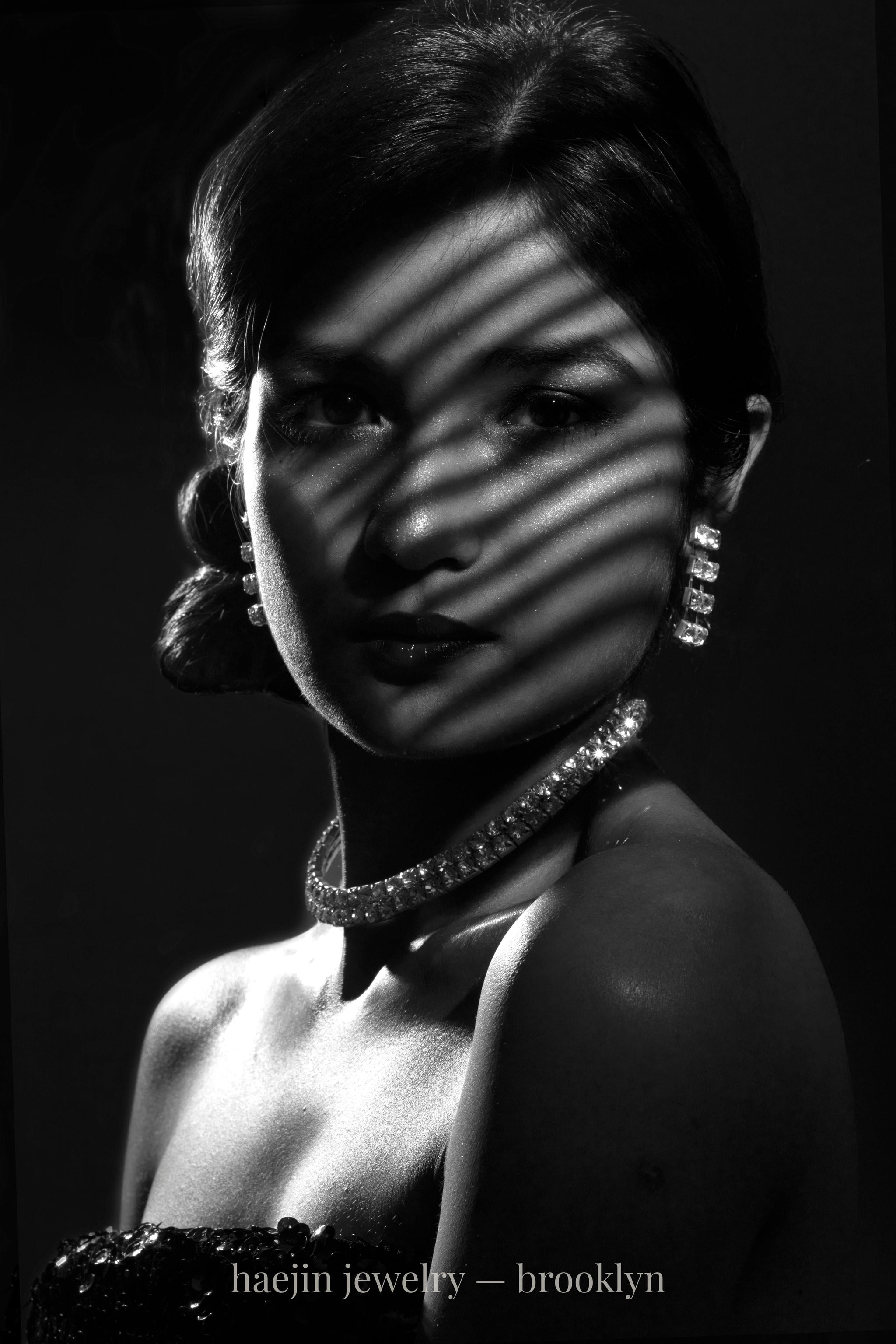 lack and white fine-jewelry portrait — woman wearing lab-grown diamond necklace and earrings by Haejin Jewelry in Brooklyn, captured in cinematic light and shadow.