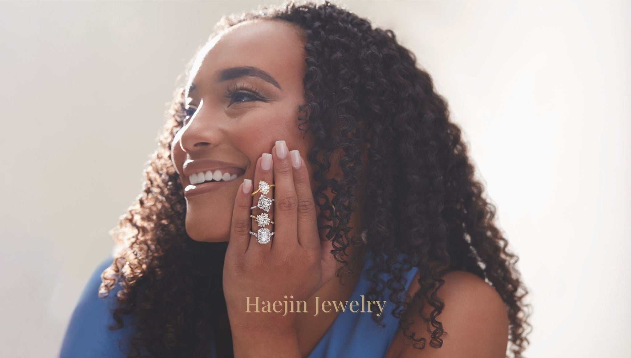 Woman smiling in warm golden hour light wearing multiple lab grown diamond engagement rings in yellow, white, and rose gold, styled by Haejin Jewelry in Williamsburg, Brooklyn.